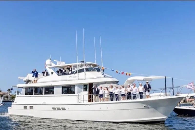 Slide: The Image of 1998 Hatteras 70 Cockpit Motor Yacht with people on deck, sailing on a sunny day. - 49