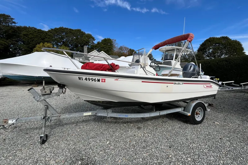 The Image of 2001 Boston Whaler 16 Dauntless boat on trailer, parked outdoors under blue sky. - 0