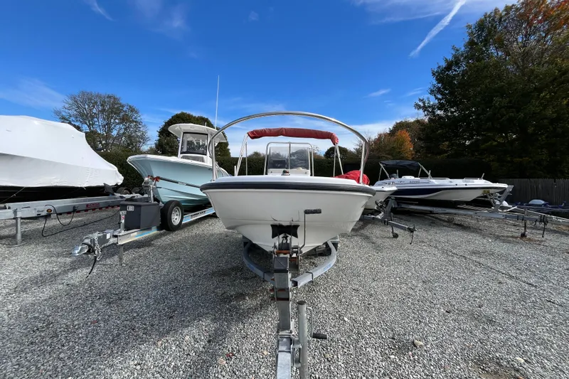 Slide: The Image of 2001 Boston Whaler 16 Dauntless boat on trailer, surrounded by other boats, under clear blue sky. - 13