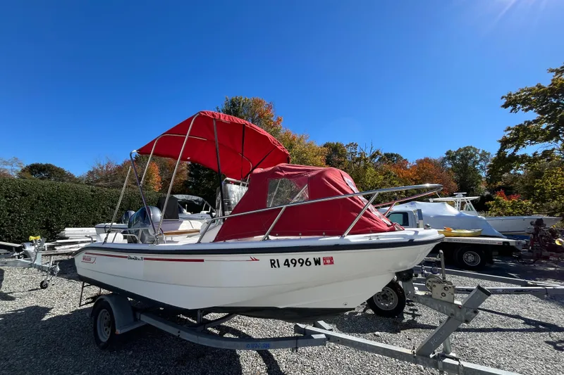 Slide: The Image of 2001 Boston Whaler 16 Dauntless boat with red canopy on trailer, parked outdoors. - 3