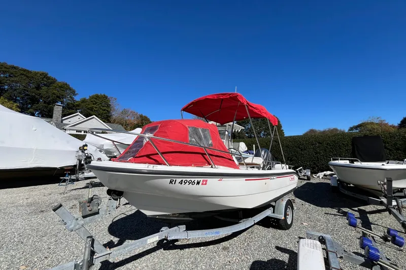 Slide: The Image of 2001 Boston Whaler 16 Dauntless boat with red canopy on a trailer, parked outdoors. - 4