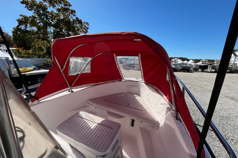 Slide: The Image of 2001 Boston Whaler 16 Dauntless boat with red canopy, docked outdoors. - 6