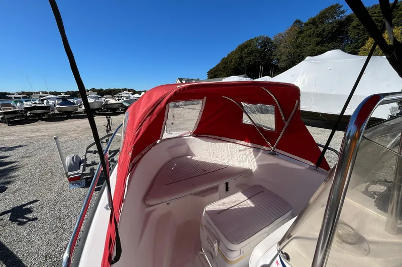 Slide: The Image of 2001 Boston Whaler 16 Dauntless with red canopy, parked among other boats. - 7