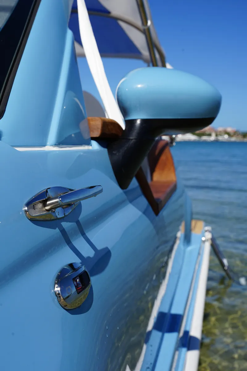 Slide: The Image of 2025 Car Off-shore Fiat 500 Classic in blue, parked by the water. - 15