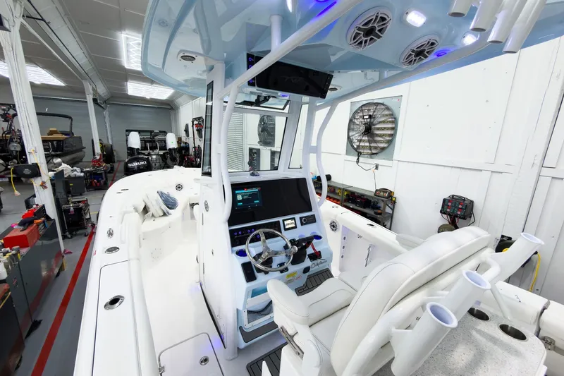 Slide: The Image of 2026 Tidewater 256 LXF boat interior with modern dashboard and seating in a workshop. - 29