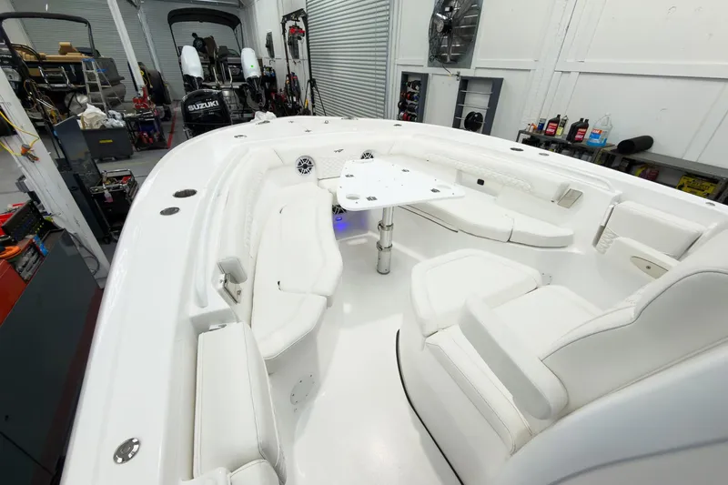 Slide: The Image of 2026 Tidewater 256 LXF boat interior with white seating and table in a garage setting. - 48