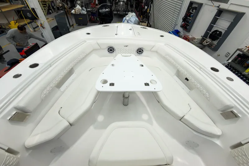 Slide: The Image of 2026 Tidewater 256 LXF boat interior with white seating and table in a workshop. - 49