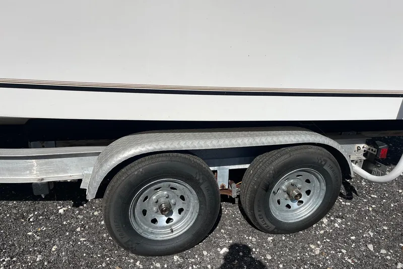 Slide: The Image of Trailer wheels of a 1995 Mako 248 boat on gravel surface. - 10