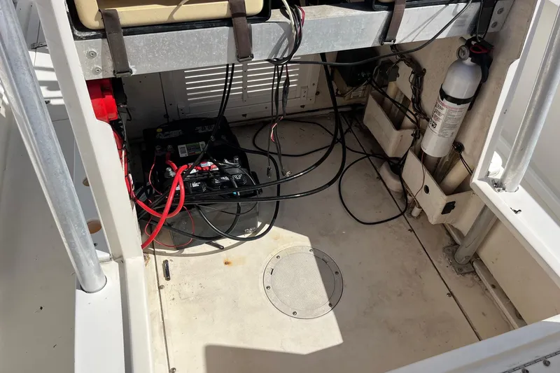 Slide: The Image of 1995 Mako 248 boat interior showing battery, wiring, and fire extinguisher setup. - 8