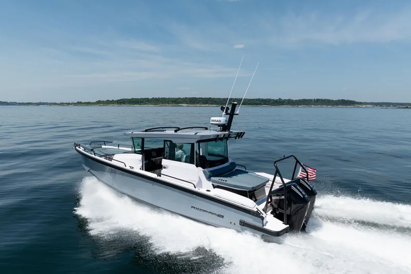 Slide: The Image of 2026 Axopar 29 Cross Cabin boat cruising on open water, clear sky background. - 12