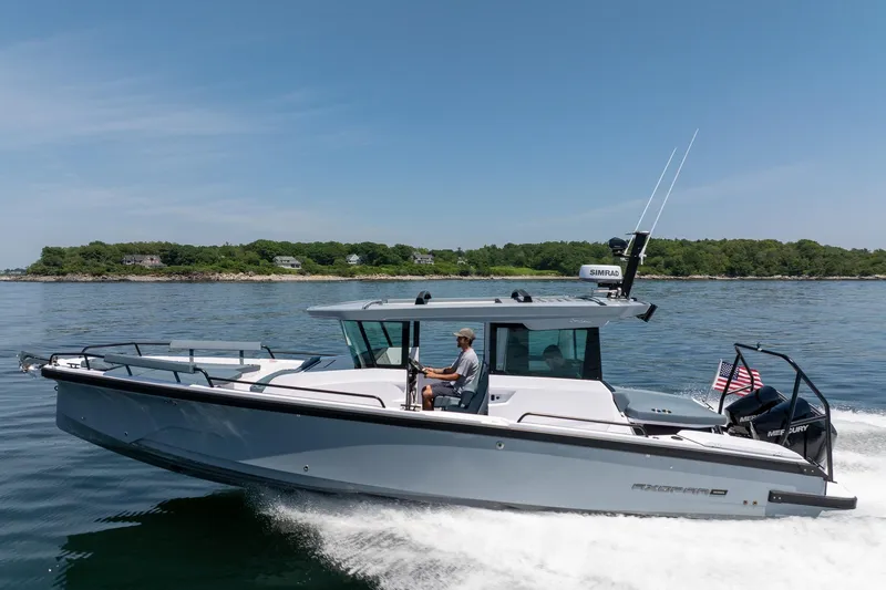 Slide: The Image of 2026 Axopar 29 Cross Cabin boat cruising on calm waters near a lush shoreline. - 16