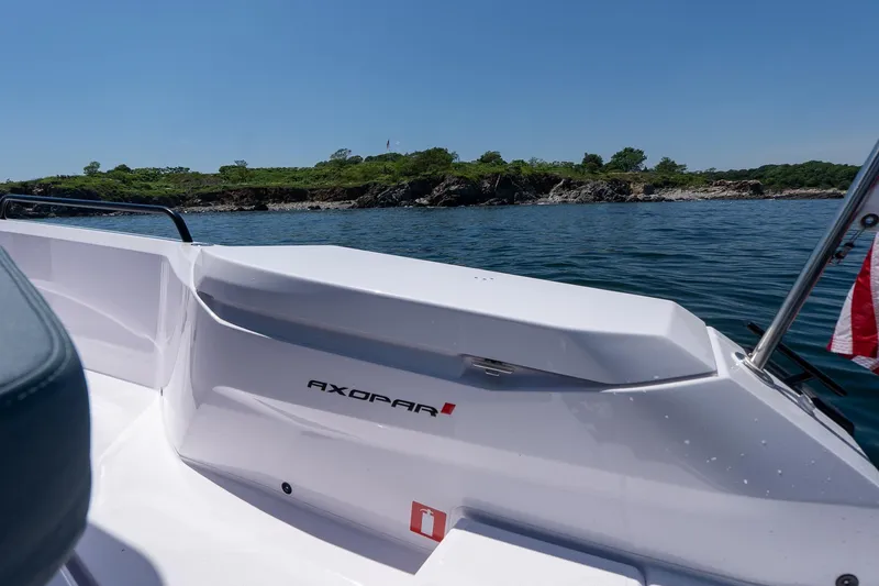 Slide: The Image of Axopar 29 Cross Cabin 2026 on water near rocky shoreline under clear blue sky. - 42