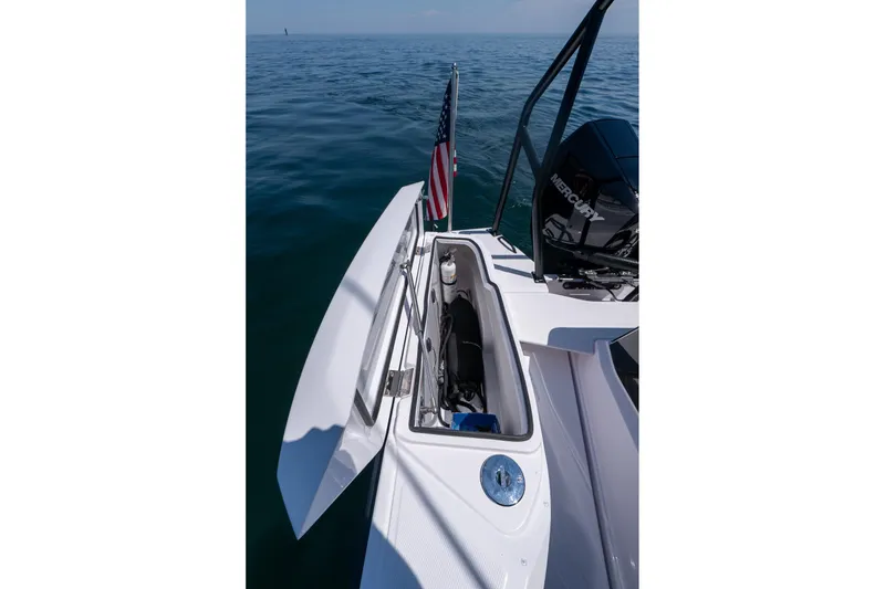 Slide: The Image of 2026 Axopar 29 Cross Cabin boat with open storage compartment on calm ocean water. - 43
