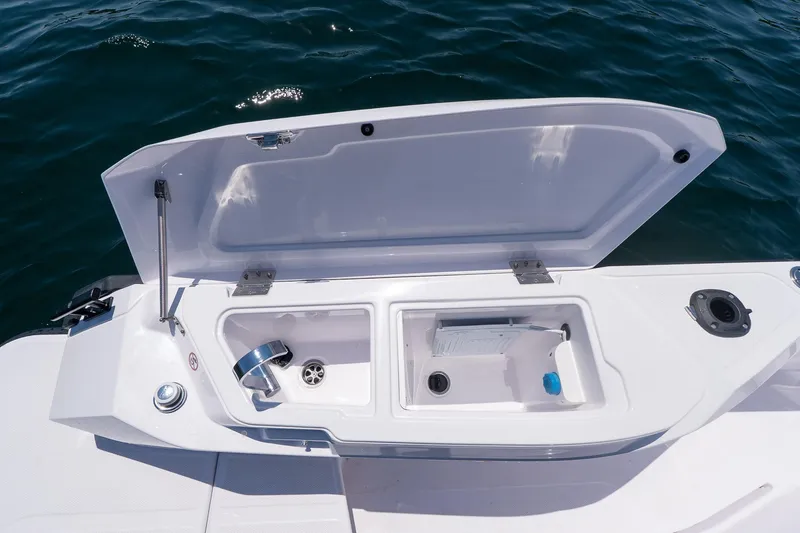 Slide: The Image of Open storage compartment on 2026 Axopar 29 Cross Cabin boat, near water. - 48