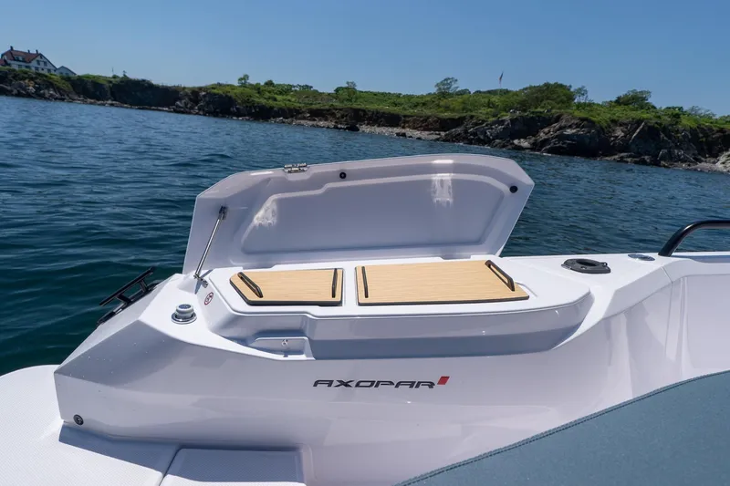 Slide: The Image of 2026 Axopar 29 Cross Cabin boat with open storage compartment, scenic coastal background. - 50