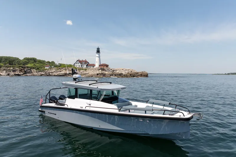 Slide: The Image of 2026 Axopar 29 Cross Cabin boat near a scenic lighthouse on a sunny day. - 6