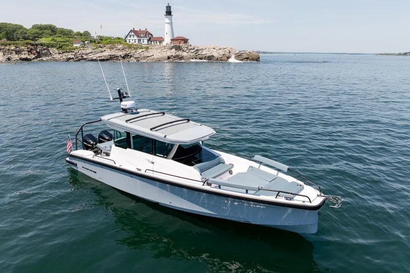 Slide: The Image of 2026 Axopar 29 Cross Cabin boat near a lighthouse on calm waters. - 7