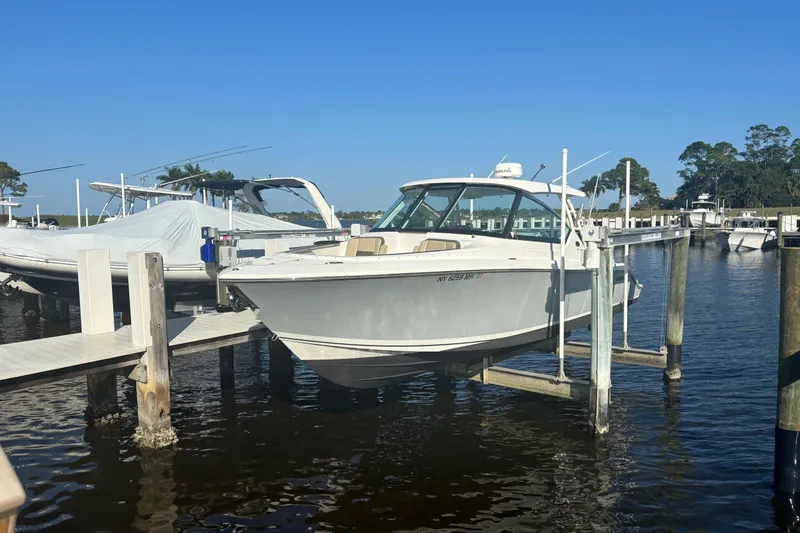 Slide: The Image of 2020 Pursuit DC 295 Dual Console boat docked at marina on a sunny day. - 1