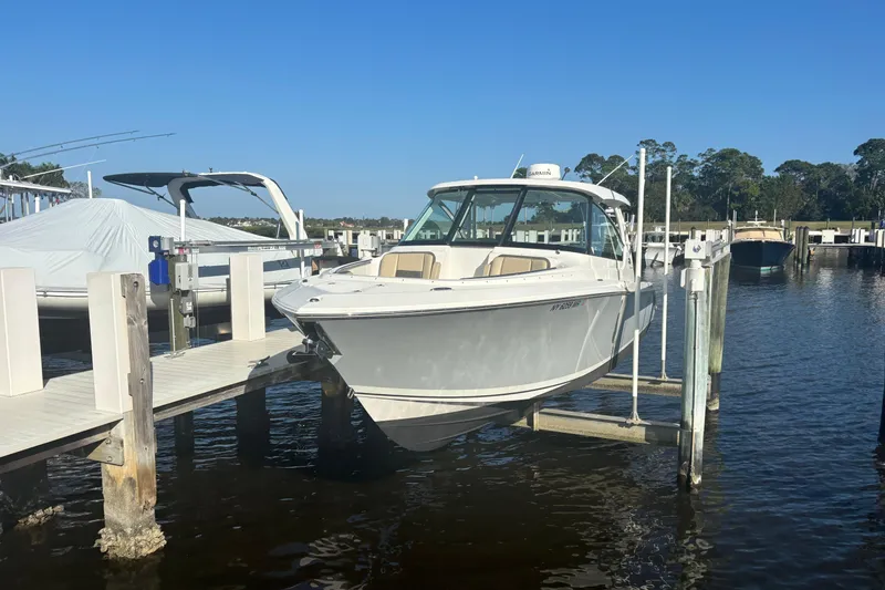Slide: The Image of 2020 Pursuit DC 295 Dual Console boat docked at marina under clear blue sky. - 2