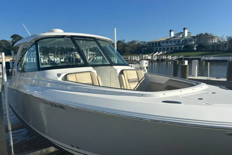 Slide: The Image of 2020 Pursuit DC 295 Dual Console boat docked at marina under clear blue sky. - 3