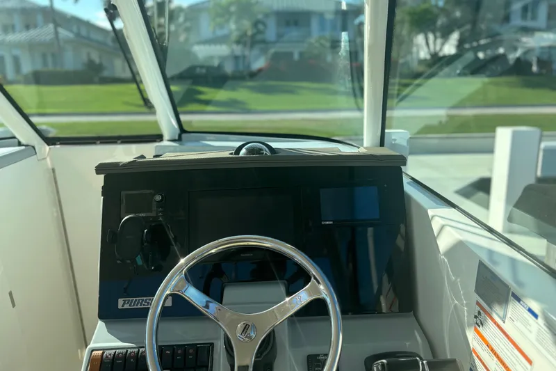 Slide: The Image of 2020 Pursuit DC 295 Dual Console boat dashboard with steering wheel and navigation controls. - 8