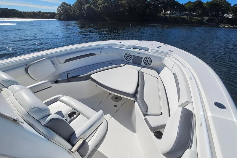 Slide: The Image of 2018 Tidewater 280 CC Adventure boat interior with cushioned seating and table on calm water. - 18