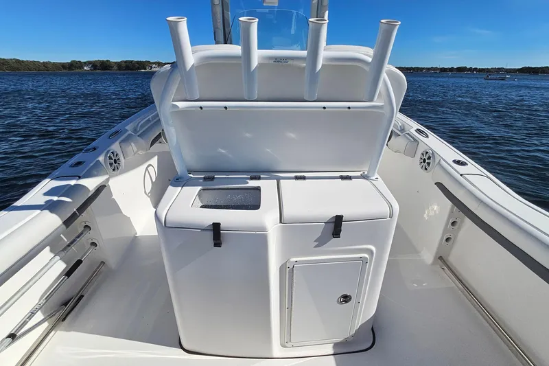 Slide: The Image of 2018 Tidewater 280 CC Adventure boat interior with rod holders and storage, on calm water. - 38