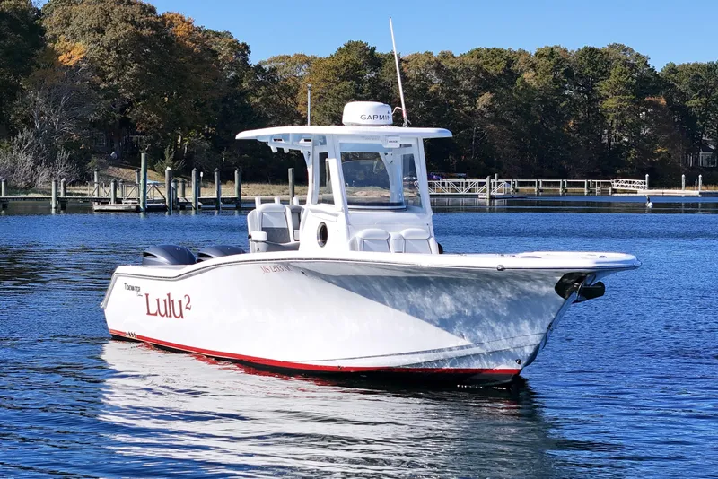 Slide: The Image of 2018 Tidewater 280 CC Adventure boat on calm water, surrounded by trees. - 4