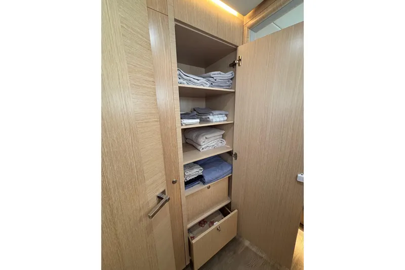 Slide: The Image of Open wooden cabinet with neatly folded towels on shelves, aboard a 2022 Seawind 1600. - 28