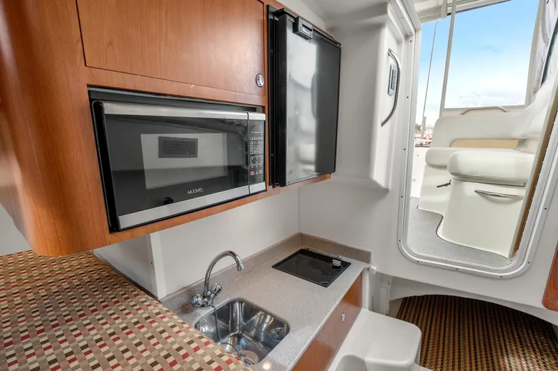 Slide: The Image of 2017 World Cat 320 EC boat interior with kitchenette, featuring microwave, sink, and compact fridge. - 30