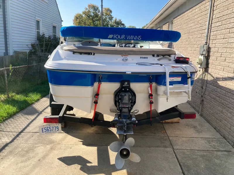 Slide: The Image of 2008 Four Winns 180 Horizon boat on trailer, parked in driveway, with blue canopy. - 26