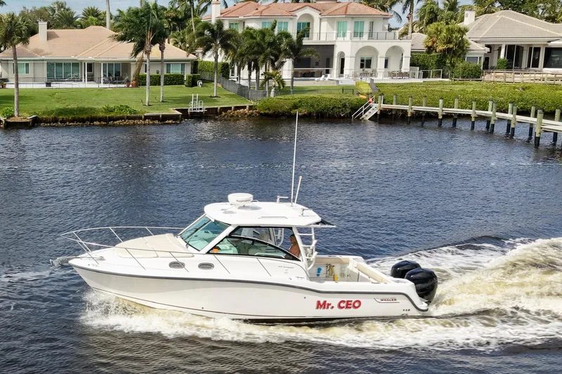 Slide: The Image of 2015 Boston Whaler 315 Conquest boat cruising on a scenic waterway near luxury homes. - 25
