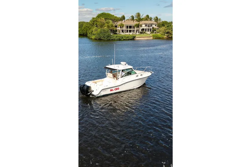 Slide: The Image of 2015 Boston Whaler 315 Conquest boat on a serene waterway near a luxury home. - 36