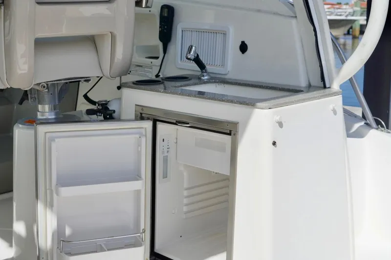 Slide: The Image of 2015 Boston Whaler 315 Conquest boat interior with open fridge and sink. - 9