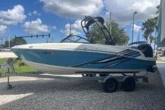 Slide: The Image of 2023 Bayliner VR5 Bowrider OB boat on trailer, blue and white design, parked outdoors. - 4