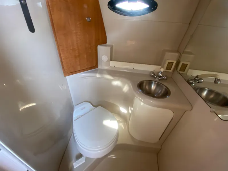 Slide: The Image of 2004 Regal 2665 Commodore boat bathroom with toilet, sink, and mirror. - 27