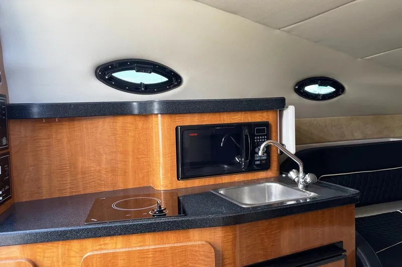 Slide: The Image of 2004 Regal Commodore 2665 boat interior with kitchenette, featuring microwave, sink, and stove. - 32