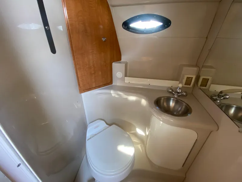 Slide: The Image of 2004 Regal 2665 Commodore boat bathroom with toilet, sink, and wooden cabinet. - 36
