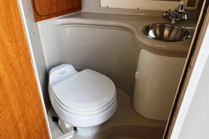 Slide: The Image of 2004 Regal Commodore 2665 boat bathroom with toilet, sink, and wooden cabinetry. - 38