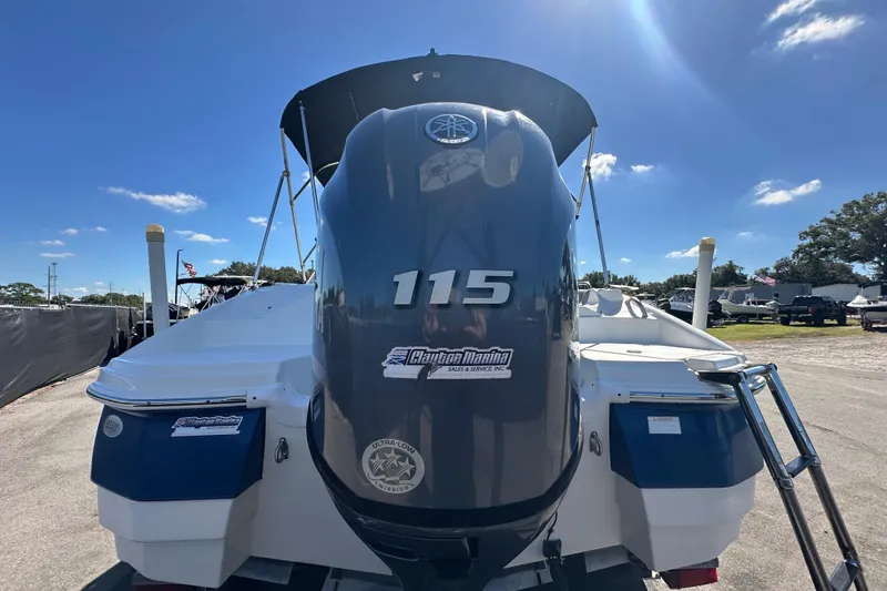 Slide: The Image of 2021 NauticStar 203 DC boat with 115 horsepower engine, parked outdoors under clear sky. - 13