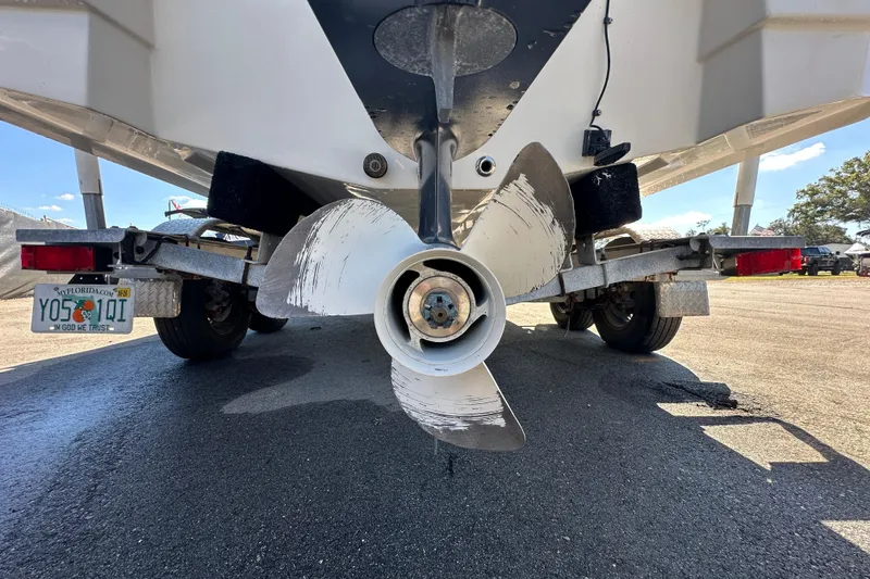 Slide: The Image of 2021 NauticStar 203 DC boat propeller and trailer, rear view on pavement. - 14