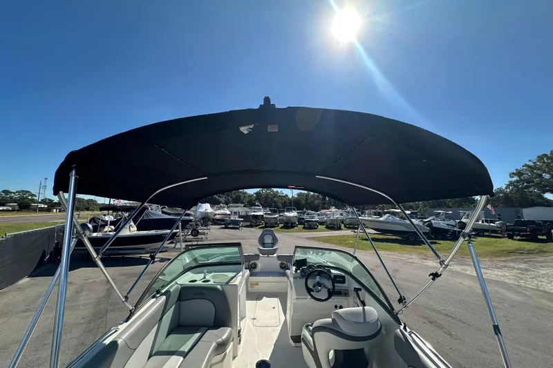 Slide: The Image of 2021 NauticStar 203 DC boat with canopy, parked under a bright sun in a marina. - 15
