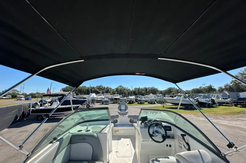Slide: The Image of 2021 NauticStar 203 DC boat interior with canopy, parked in a marina. - 18