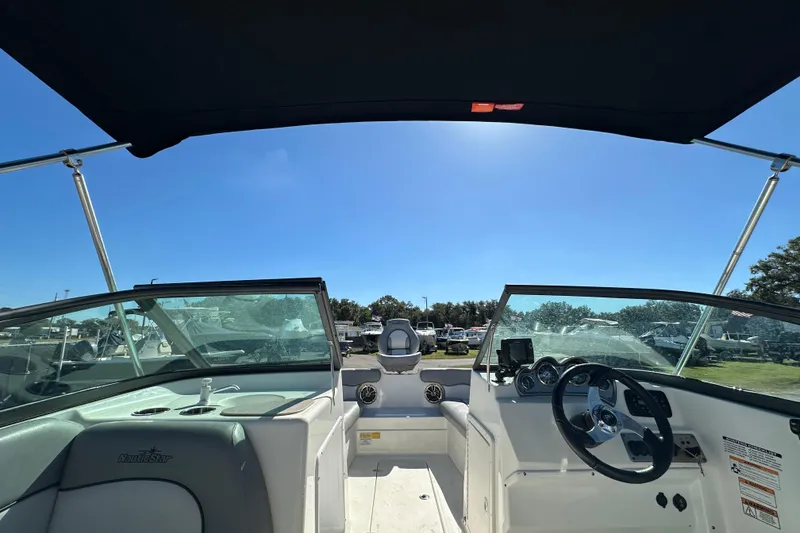Slide: The Image of 2021 NauticStar 203 DC boat interior with steering wheel and dashboard under canopy. - 23