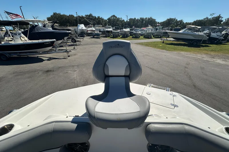 Slide: The Image of 2021 NauticStar 203 DC boat seat view at a marina with multiple boats. - 51