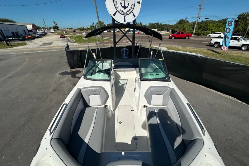 Slide: The Image of 2021 NauticStar 203 DC boat with spacious seating, parked outdoors under clear blue sky. - 60