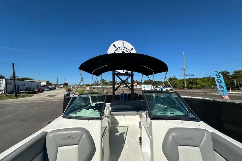 Slide: The Image of 2021 NauticStar 203 DC boat with canopy, parked on a sunny day near a road. - 62