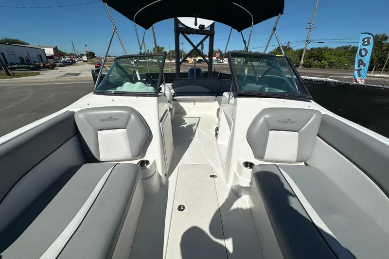 Slide: The Image of 2021 NauticStar 203 DC boat interior with seating and windshield, parked outdoors. - 63
