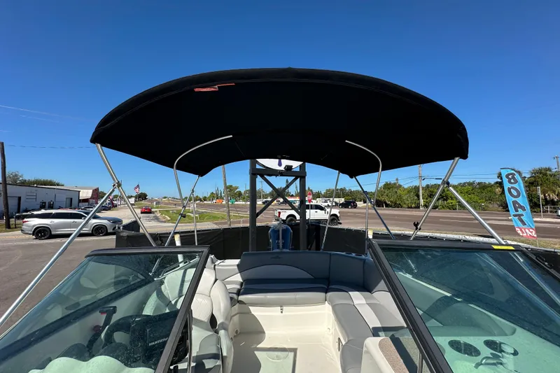 Slide: The Image of 2021 NauticStar 203 DC boat with canopy, parked outdoors under clear blue sky. - 68