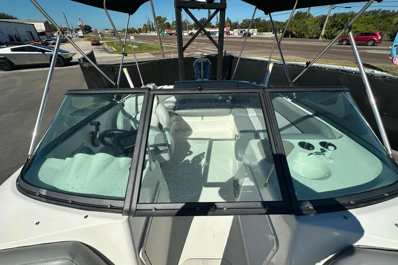 Slide: The Image of 2021 NauticStar 203 DC boat interior with seating and steering wheel, parked outdoors. - 70